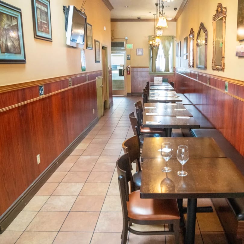 Sage Bistro's dining area with tables, chairs, and banquette seating along a wood-paneled wall.