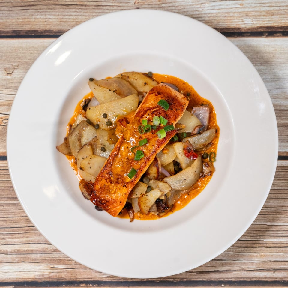 Sage Bistro's salmon fillet with roasted potatoes and capers, drizzled with orange sauce.