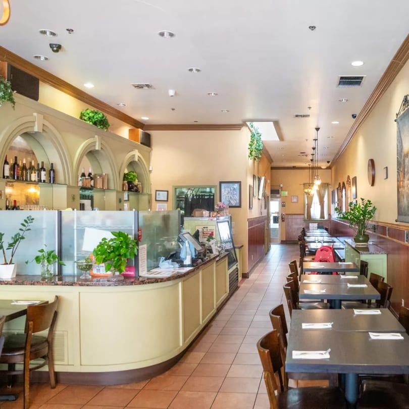 Sage Bistro's dining room features a counter with arched shelving and a long row of set tables.